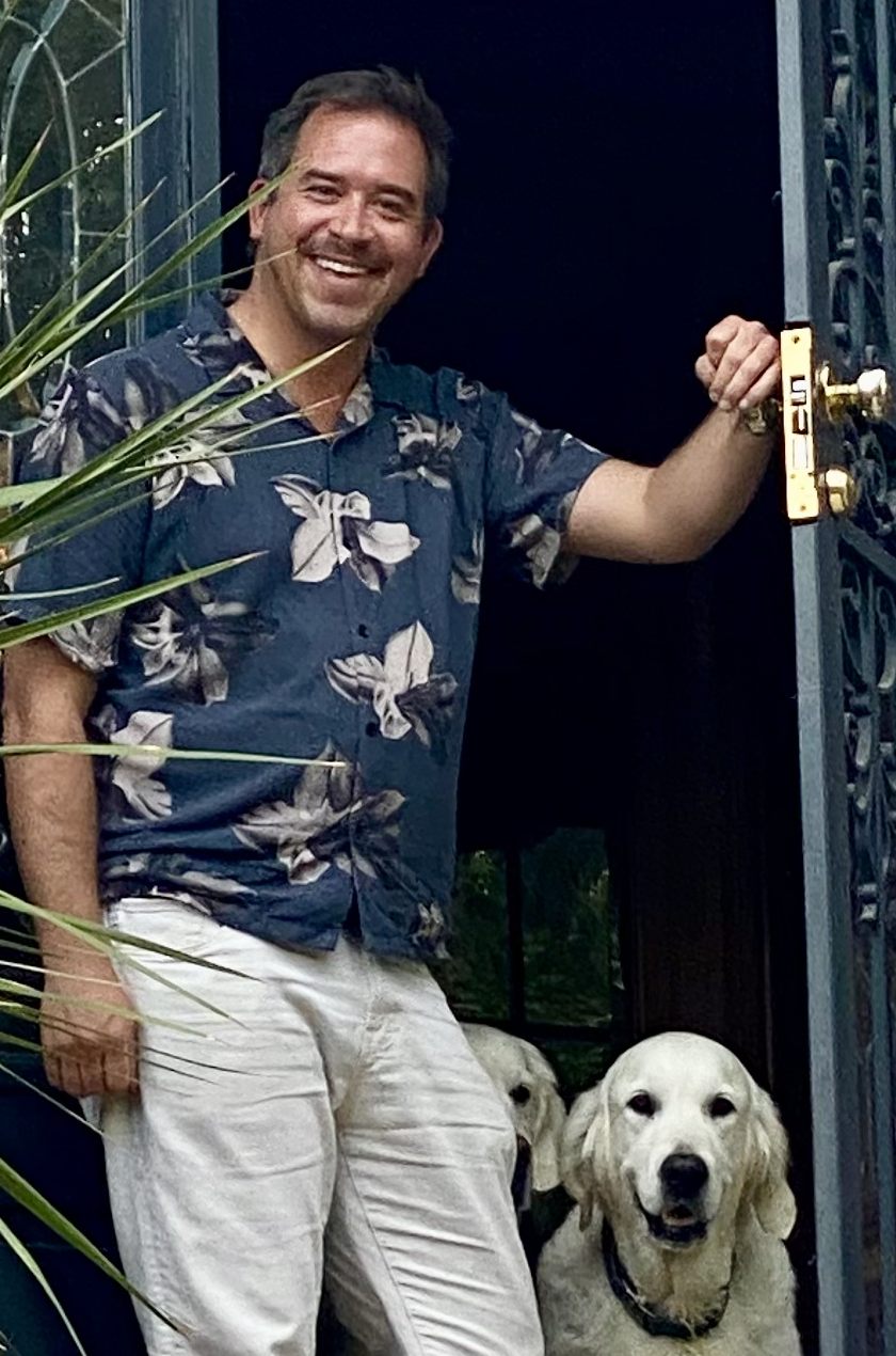 Dr. Patrick Long in an open doorway with two golden retrievers.